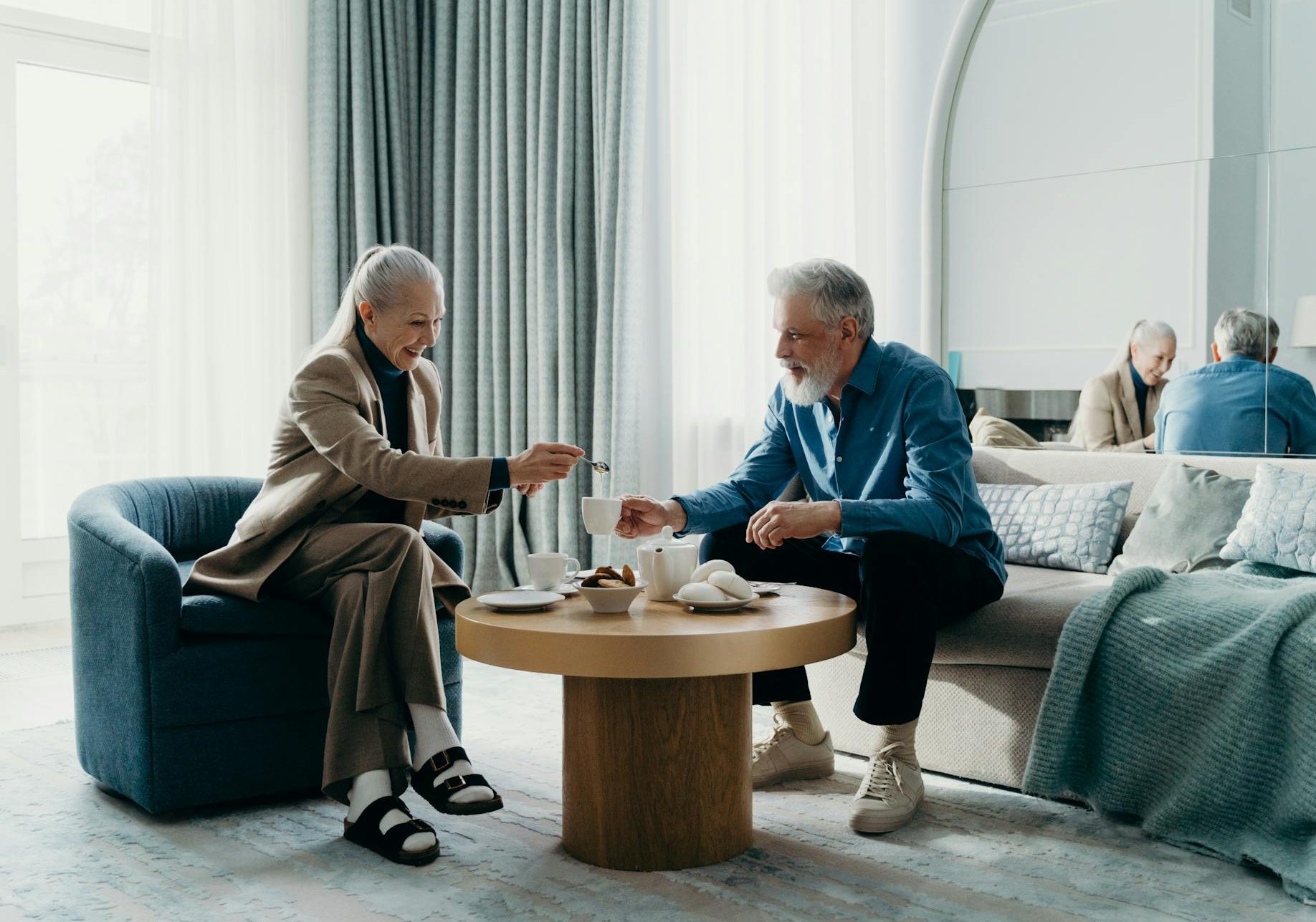Elderly couple relaxing with coffee indoors, enjoying leisure time together.